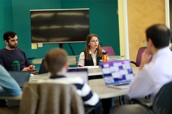 Olena Protsenko talking with students around a table