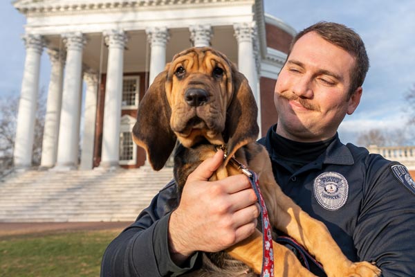 Portrait of Maggie the bloodhound and officer Logan Moore on the Lawn