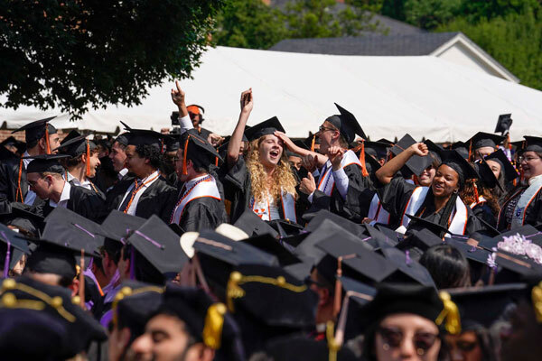 Students standing up celebrating the confirmation of their degrees