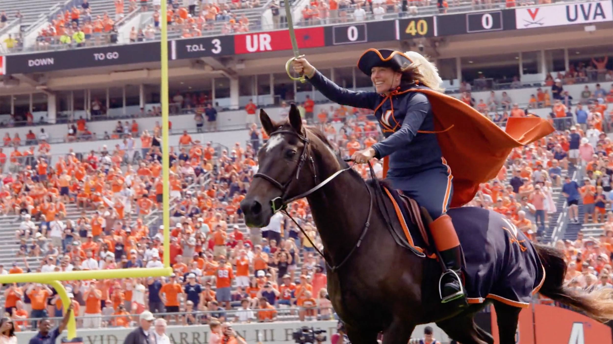 Julie riding a horse into scott stadium with Saber high