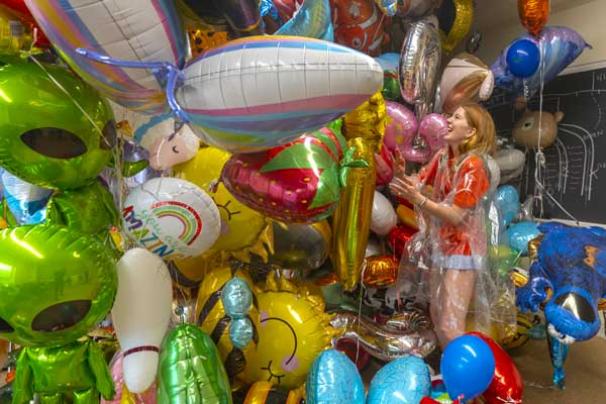 A volunteer enveloped by a mass amount of donated balloons
