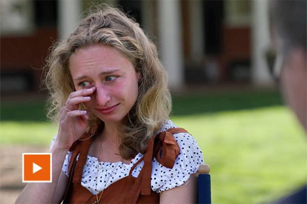 Student wipes tear away from eye as she speaks about not seeing her parents in four years
